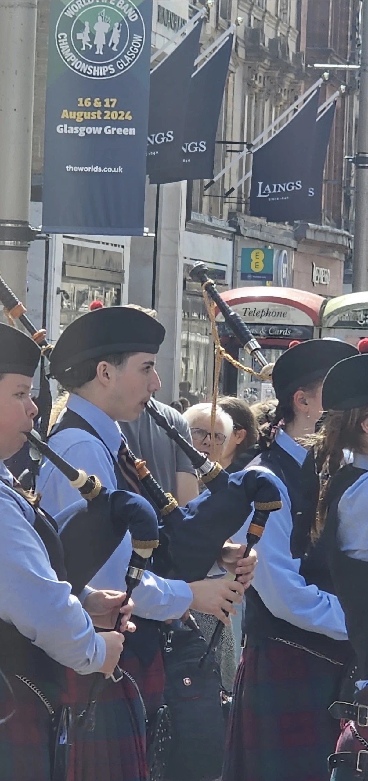 Sergio playing the bagpipes with fellow pipers on a street in Glasgow